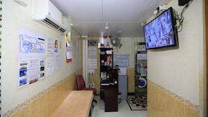 A small office with a desk, chair, and a computer. There are posters on the wall and a television mounted on the wall. - Everest Hostel Block E (Kowloon)