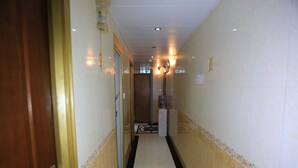 A narrow hallway with a tiled floor, a water dispenser, and a door on the left. - Everest Hostel Block E (Kowloon)