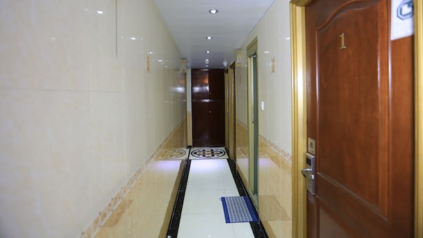 A hallway with a tiled floor, a wooden door labeled '1', and a glass door with a metal handle. - Everest Hostel Block E (Kowloon)