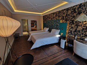 Une chambre d’hôtel avec deux lits, une lampe de sol, une table de chevet et une lampe fixée au mur.