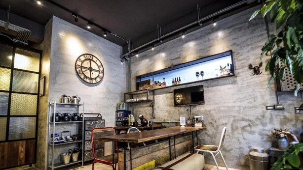 A bar area with a wooden counter, metal chairs, and a large clock on the wall. - You Worth Inn (Hualien City)