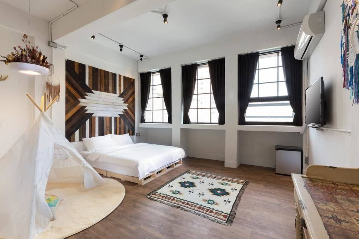Un dormitorio moderno con una cama, un dosel blanco, un tapete estampado y un ventanal con cortinas.