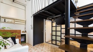 A modern interior with a staircase, a white sofa, and a tiled floor. - You Worth Inn (Hualien City)