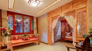 Una habitación tradicional con un sofá de madera, un escritorio de madera y una cama con dosel.