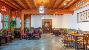 Un interior de madera tradicional con una zona de comedor central, vigas de madera y un colgador de luz.
