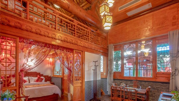 Una habitación de madera tradicional con cama, una mesa de comedor y una ventana con vidrieras decorativas.