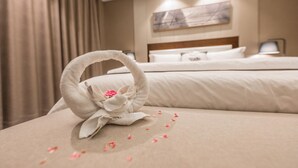 Een opgemaakt bed met handdoek en bloemenopstelling op het beddegoed.