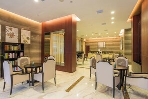 Eine Hotelhalle mit einer Rezeption, einer Sitzecke und einem Bücherregal.