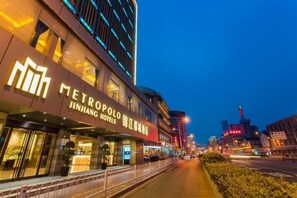 A hotel with a modern facade, signage for 'METROPOLIO JINJIANG HOTELS,' and a well-lit entrance. - Metropolo Jinjiang Hotels (Xuzhou Railway Station, Suning Plaza, Chudu) (Xuzhou)