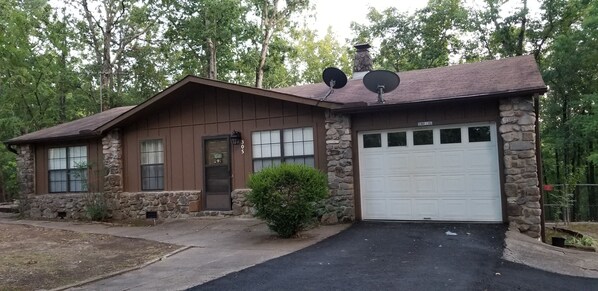 A two-story house with a stone facade, a brown wooden exterior, and a white garage door. - Canterbury Cabin (Hot Springs)