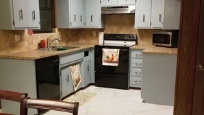 A kitchen with light blue cabinets, a stove, a microwave, and a dining table with chairs. - Canterbury Cabin (Hot Springs)
