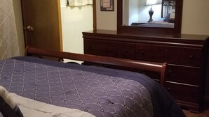 A bedroom with a bed, dresser, and a mirror. - Canterbury Cabin (Hot Springs)