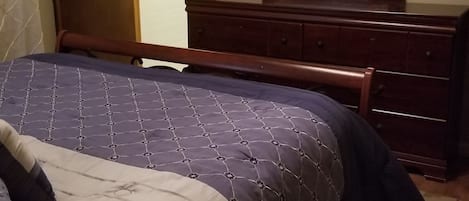 A bedroom with a bed, dresser, and a mirror.