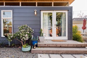 Une maison moderne avec une façade de couleur gris foncé, une terrasse en bois et une porte vitrée donnant sur un espace patio.