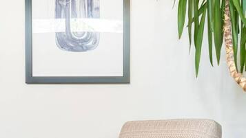 A beige armchair with a herringbone pattern, a blue pillow, and a wooden frame.