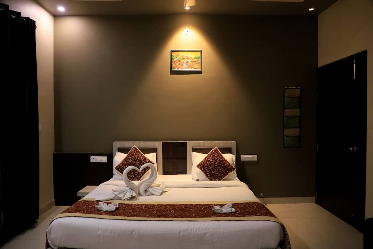 A hotel room with a large bed, two nightstands, a wall-mounted artwork, and a door with a towel rack.