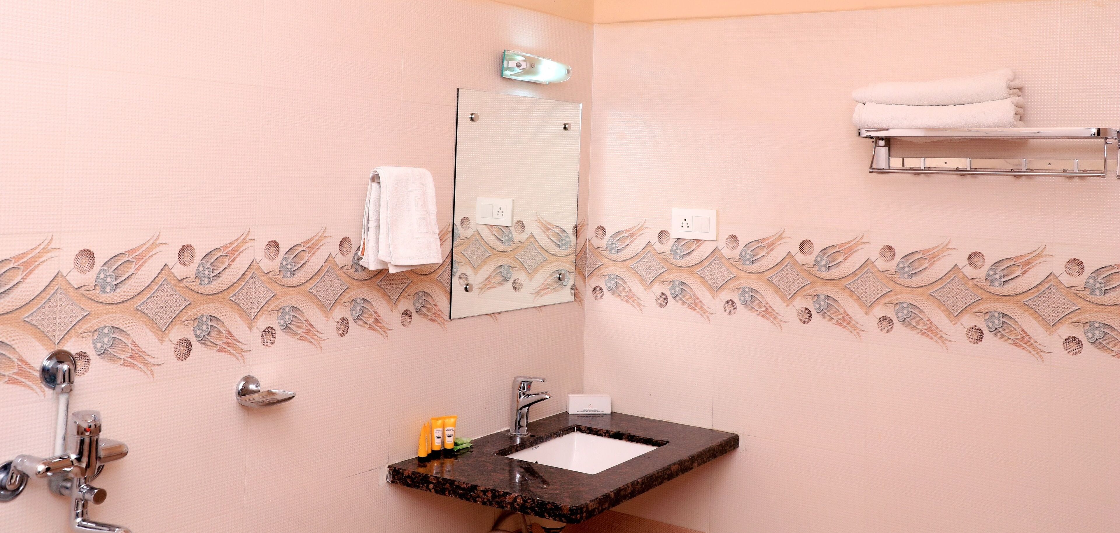 A bathroom with a sink, mirror, towel rack, and decorative wall tiles.