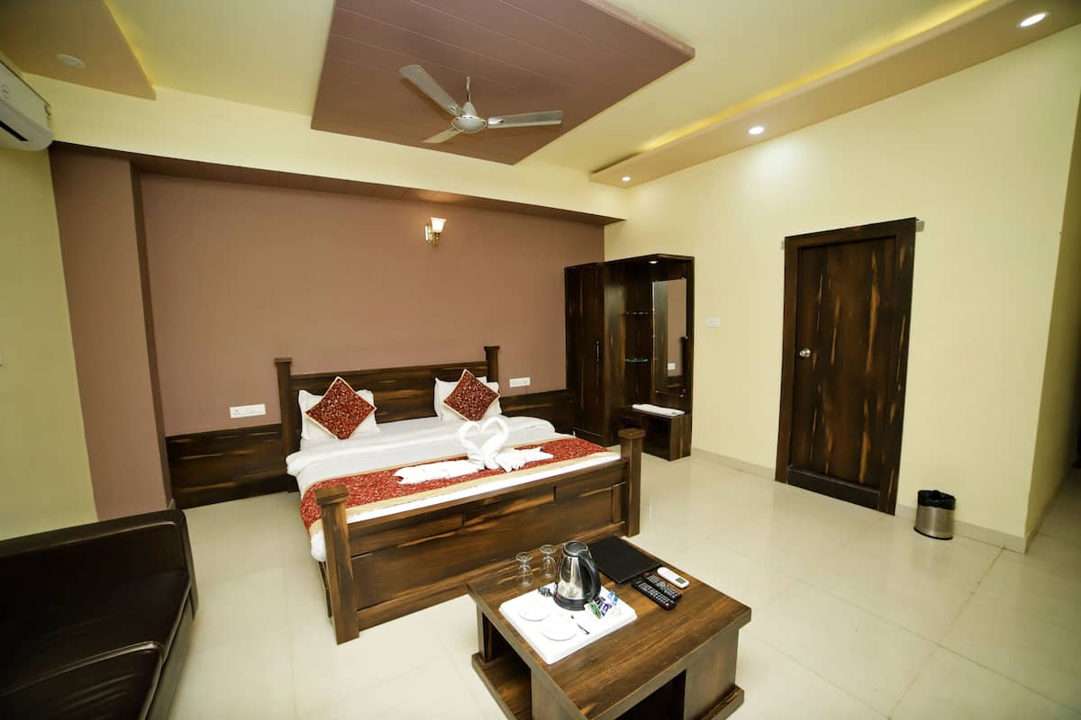 A hotel room with a large bed, a wooden nightstand, a ceiling fan, and a door.