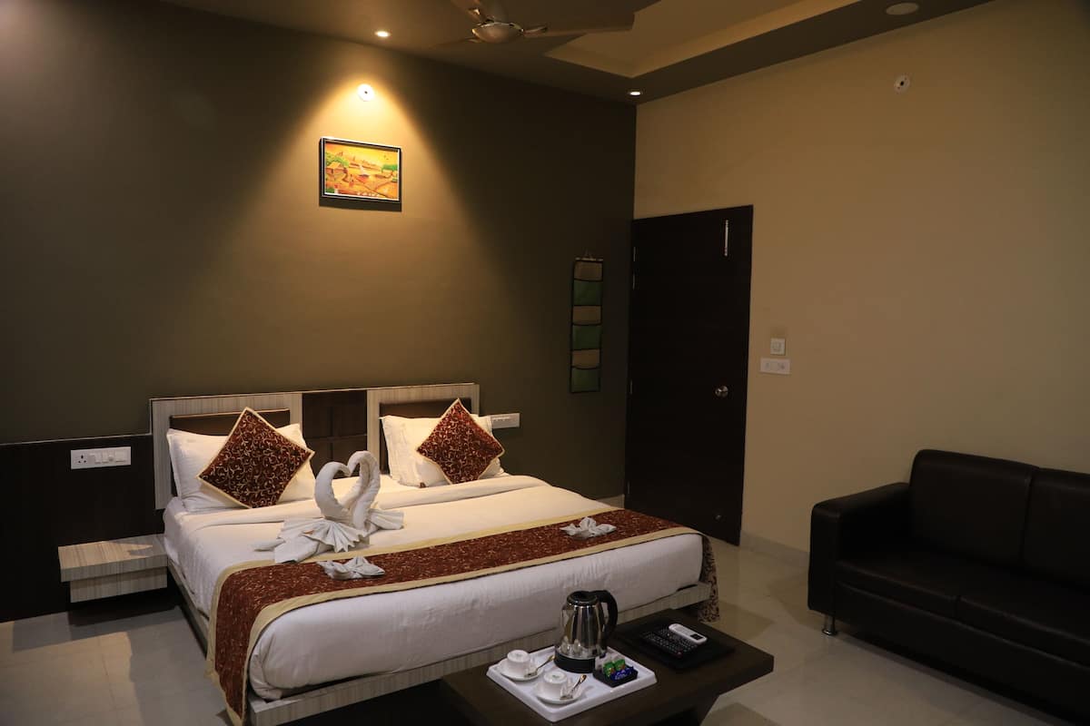A hotel room with a bed, a coffee table, a sofa, and a painting on the wall.