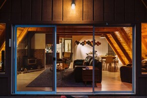 A cozy living room with a fireplace, a dining area, and a staircase leading to an upper level.