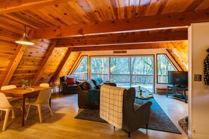 A cozy, wooden interior with a dining area, seating, and a TV.