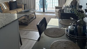 Un espaiós saló amb un sofà, una taula de menjador amb cadires, una cuina i un balcó amb vistes.