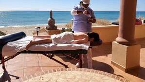 A massage therapy session on a beachside terrace with a view of the sea.