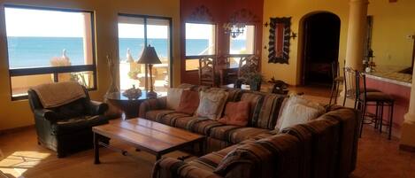 A living room with a sofa, armchair, and a view of the ocean.