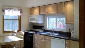 A compact kitchen with wooden cabinets, a microwave, a stove, and a dishwasher. - The Cabin at Chichester in the Catskills Mountains (Chichester)