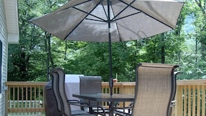 An outdoor patio with a table and chairs, a large umbrella, and a wooden deck. - The Cabin at Chichester in the Catskills Mountains (Chichester)