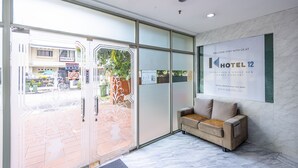 A hotel reception area with a glass door, a sofa, and a large welcome sign. - K HOTEL 12 (Singapore)
