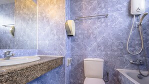 A bathroom with a granite countertop sink, a toilet, and a bathtub with a handheld showerhead. - K HOTEL 12 (Singapore)