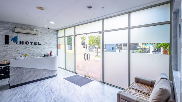 A hotel reception area with a marble counter, a reception desk, a seating area with a sofa, and large glass doors leading outside. - K HOTEL 12 (Singapore)