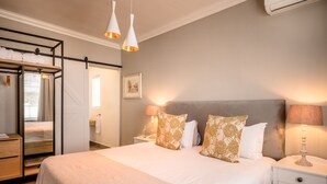 A neatly arranged bedroom with a large bed, bedside lamps, a wardrobe, and a mirror.