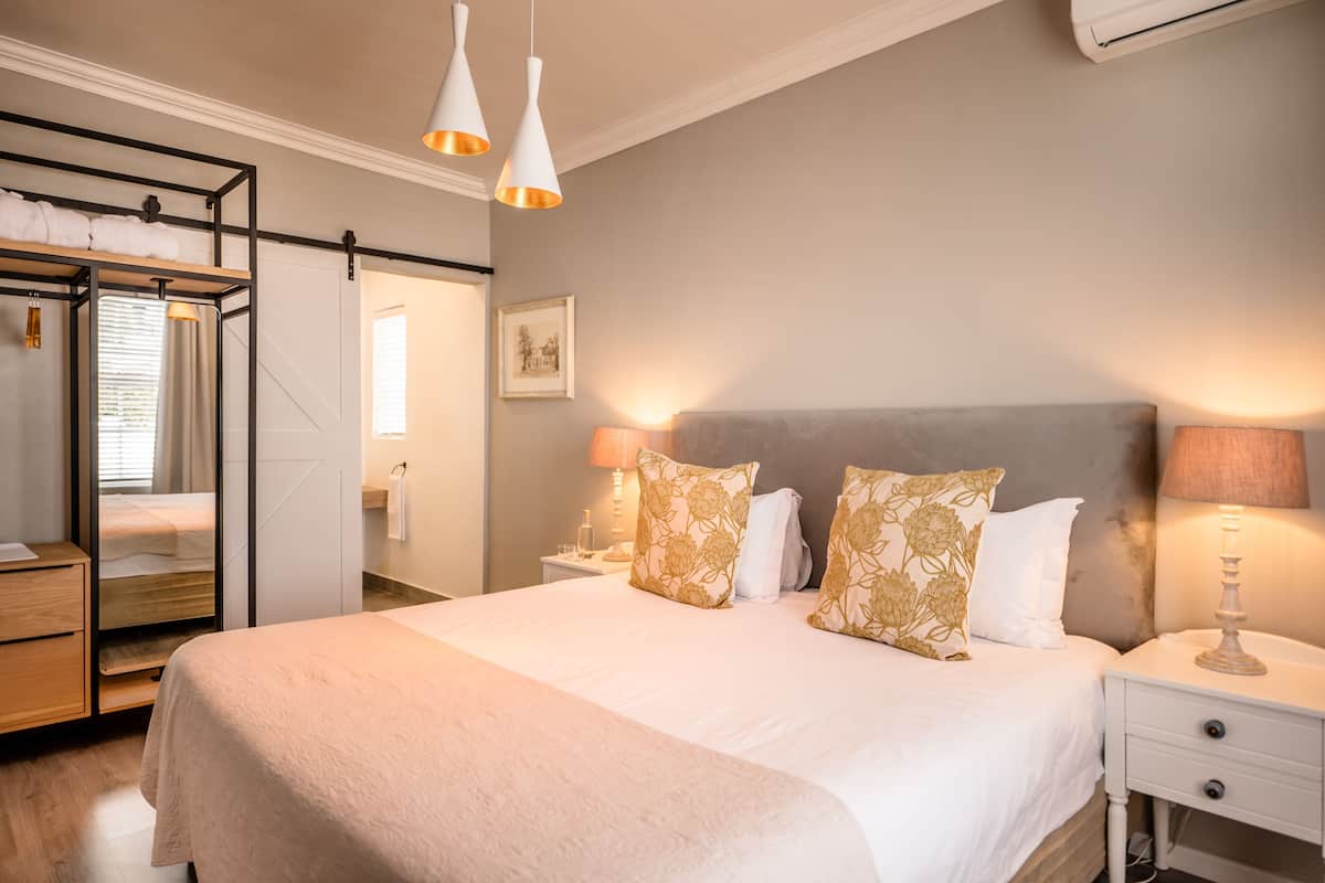 A neatly arranged bedroom with a large bed, bedside lamps, a wardrobe, and a mirror.