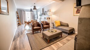 A modern living room with a sofa, chairs, a coffee table, and a kitchen in the background.