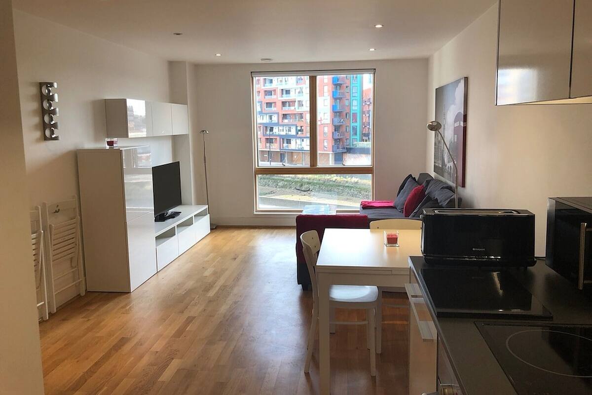 Un appartement moderne doté d’une cuisine, d’un coin repas et d’une grande fenêtre donnant sur la ville.