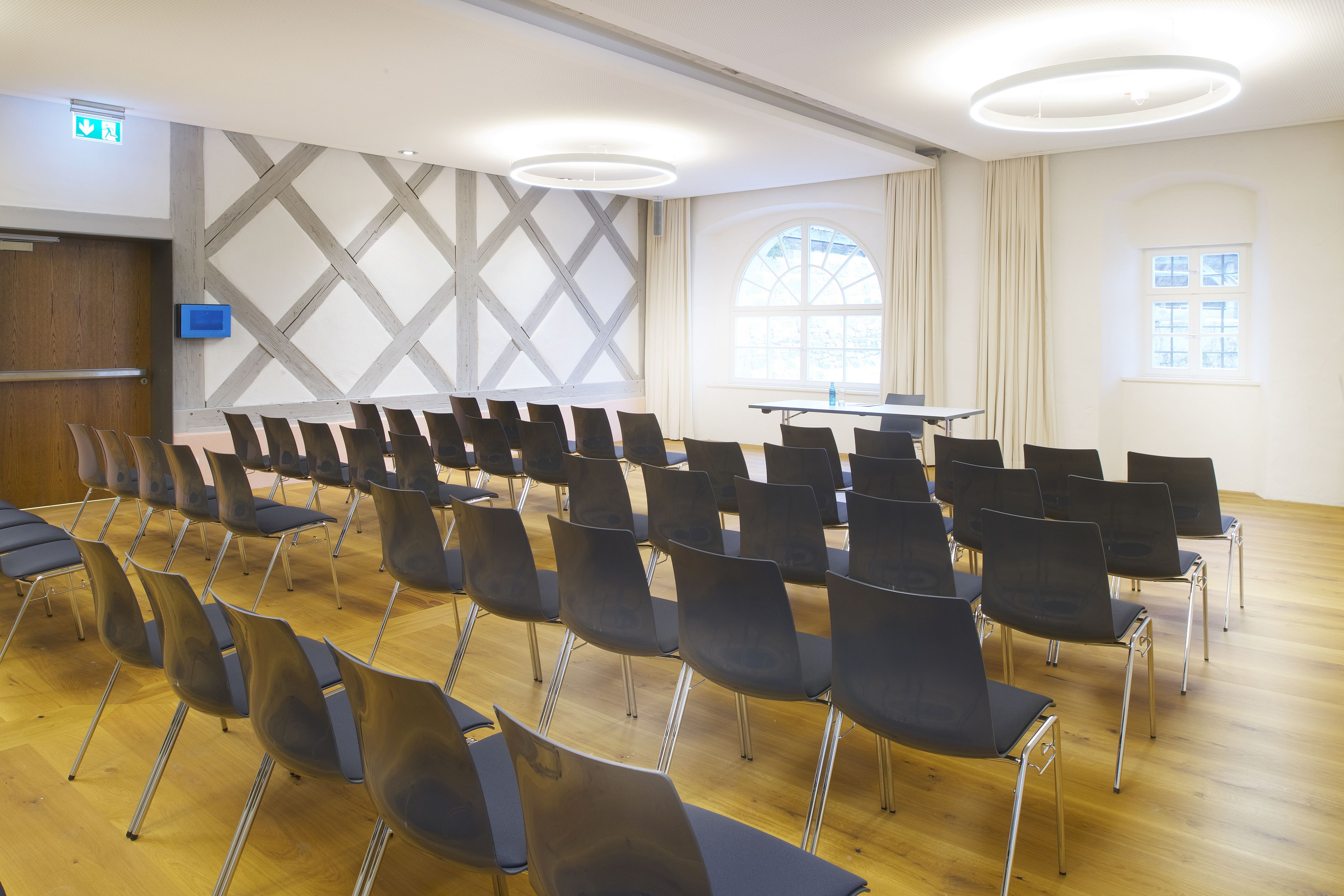 A conference room with rows of chairs, a table, and large windows.