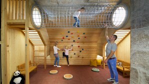 Una pared de escalada de madera con presas de colores, un peluche de panda y un banco de madera.