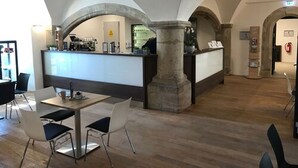 Un vestíbulo amplio con una zona de bar central, columnas de piedra y suelo de madera.