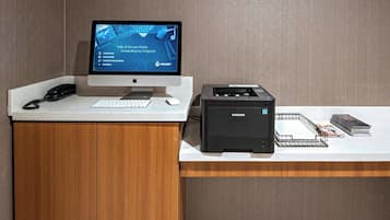 A reception desk with a computer monitor displaying a website, a phone, a keyboard, a mouse, and a printer.