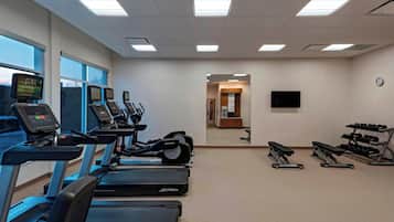 Un gimnasio con cintas de correr, elípticas y máquinas de pesas.