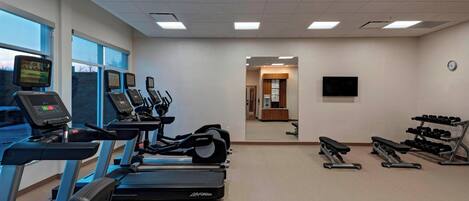Una palestra con tapis roulant, ellittiche e macchinari per l'allenamento con i pesi.