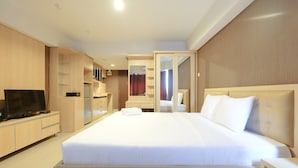 A hotel room with a large bed, a TV, a wardrobe, and a bathroom visible through an open door. - Comfortable and Modern Studio Apartment near Cawang and MT Haryono (Jakarta)