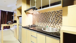 A modern kitchen with a black countertop, stainless steel sink, and a tiled backsplash. - Comfortable and Modern Studio Apartment near Cawang and MT Haryono (Jakarta)