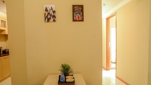 A hallway with a table in the center holding a box labeled 'Travelio' and a small plant. - Best of the Best 3BR Apartment Grand Palace/Pallazo Kemayoran (Jakarta)