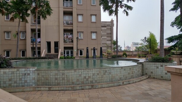 A residential building with a swimming pool, surrounded by palm trees and a tiled walkway. - Best of the Best 3BR Apartment Grand Palace/Pallazo Kemayoran (Jakarta)