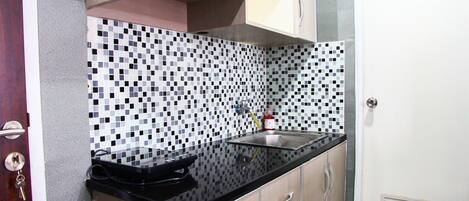 A kitchen with a black countertop, wooden cabinets, and a tiled backsplash.