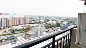 A cityscape with a view of a construction site, a crane, and a building with signage. - Best Price 2BR Mutiara Bekasi Apartment (Bekasi)