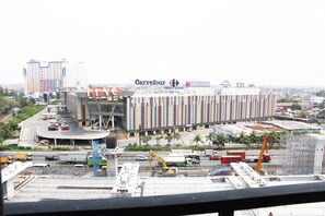 A large commercial building with multiple signs, including Carrefour and MATAHARI, surrounded by construction equipment and vehicles. - Best Price 2BR Mutiara Bekasi Apartment (Bekasi)